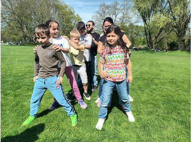 Kinder und Jugendliche stehen in zwei Reihen in einem Park in Heilbronn um das "Taußendfüßler-Spiel" zu üben.